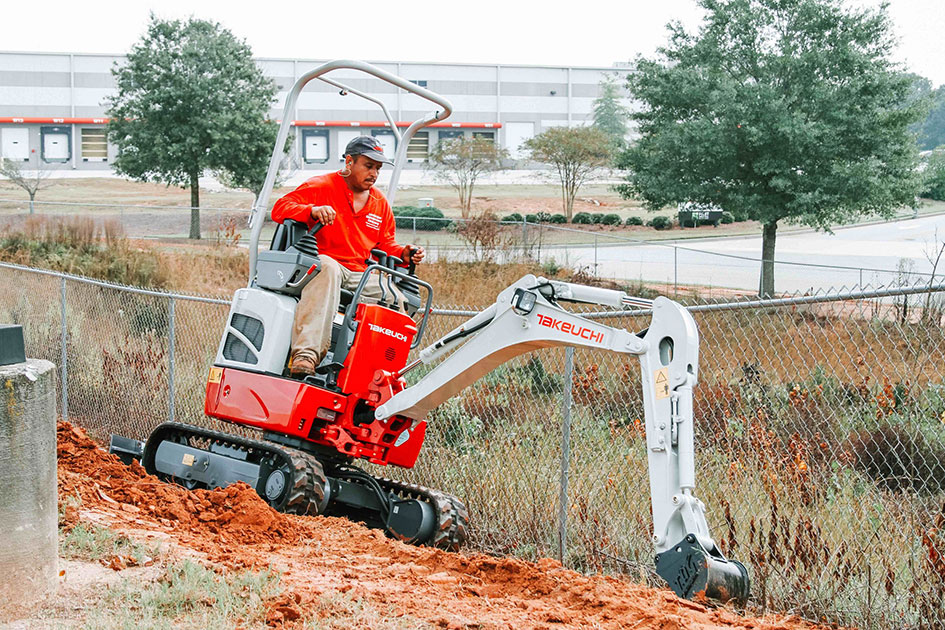 Mini-pelle Takeuchi TB210R travaillant près d’une clôture