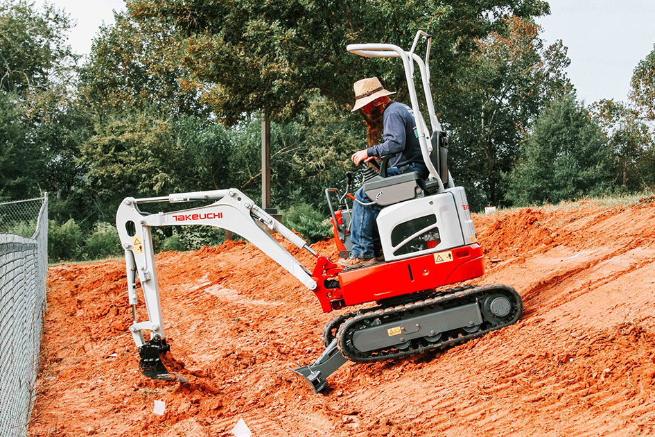 Takeuchi TB210R travaillant sur un chantier de terrassement en pente